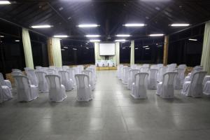 a row of white chairs in a room with a screen at Albacora Praia Hotel in Japaratinga
