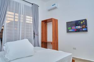 a bedroom with a bed and a window and a tv at Villa Maisha in Arusha