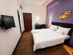 a bedroom with a white bed and a flat screen tv at Subhas Tourist Hotel in Jaffna