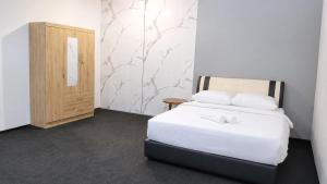 a bedroom with a white bed and a wooden door at Neela Homestay in Labuan