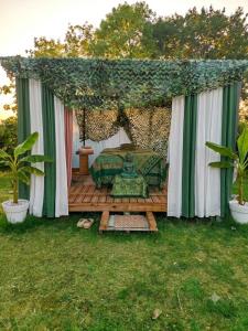 a gazebo with a couch on a wooden deck at Les pieds dans l'eau Pergola in Fleurville