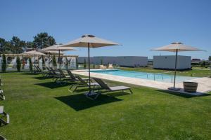 a row of chairs and umbrellas next to a pool at MJ Guest House in Póvoa de Varzim