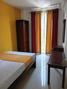 a bedroom with a bed and a table and curtains at Dil Apartments 2 in Mount Lavinia