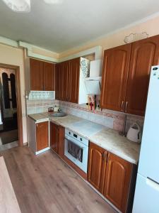 a kitchen with wooden cabinets and white appliances at Weekend Home in Visaginas