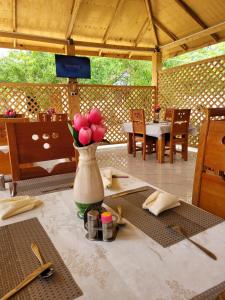 a table with a vase with pink flowers on it at Angel homestay hotel in Mikumi