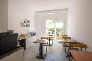 eine Küche und ein Esszimmer mit Tischen und einem Fernseher in der Unterkunft Sa Pasadina in Àrbatax