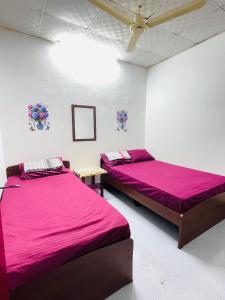 two beds in a room with pink sheets at Lathu - zen Stay Hotal in Trincomalee
