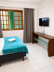 a bedroom with a bed and a desk and a television at REF House Barra Da Tijuca in Rio de Janeiro