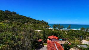 a house on a hill next to the ocean at Pousada Beira Mar in Garopaba