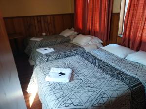 two beds in a hotel room with towels on them at Hotel Don Matías in Concepción