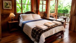 a bedroom with a bed with two towels on it at Hostería los Cedros de Mindo in Mindo +72 photos