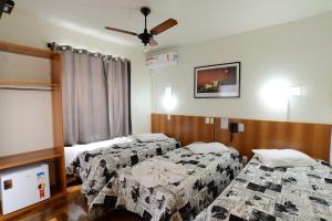 a hotel room with two beds and a ceiling fan at Bandeira Hotel in Caxias do Sul