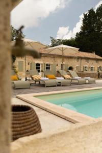 a swimming pool with lounge chairs next to a building at Maison Girardine in Rauzan