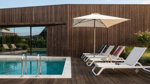 a group of lounge chairs with an umbrella next to a pool at Villã - Casas de Campo in Paredes