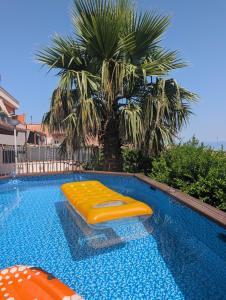 a swimming pool with two yellow inflatables next to a palm tree at Casa Malù in SantʼAlfio +50 photos