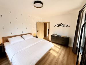 a bedroom with a white bed and a black dresser at Apartmány Perninský Dvůr in Pernink