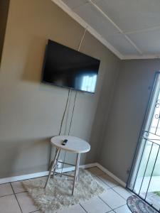 a room with a table and a tv on the wall at Ocean River no 1 in Gqeberha