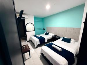 a hotel room with two beds with blue walls at Hotel Exito Barranquilla in Barranquilla