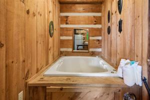 a bathroom with a tub in a wooden cabin at Sequoyah by Venture Smoky Mountains in Cartertown +60 photos