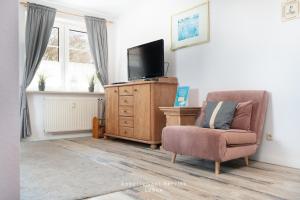 a living room with a chair and a flat screen tv at Wiesenweg W10 in Laboe