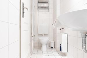 a white bathroom with a toilet and a sink at Wiesenweg W10 in Laboe +21 photos