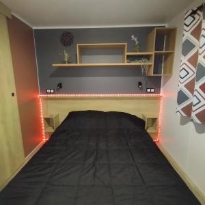 a bedroom with a bed with lights on it at Terracotta Lodge - Un cocon chaleureux pour des vacances inoubliables in Nibelle