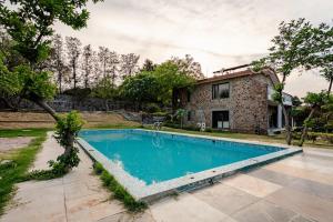 an image of a swimming pool in front of a house at Aravali view Farmhouse in Gurgaon