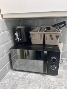 a black microwave with a basket on top of it at Quiet Double Room Ensuite Marble Bathroom South Croydon in Croydon
