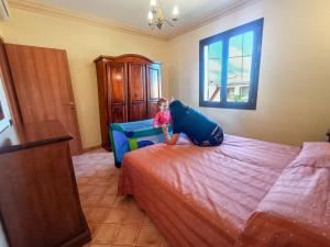 a little girl playing on a bed in a bedroom at Bilo 4 in Triscina