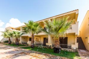 a row of palm trees in front of a building at Bilo 4 in Triscina +12 photos