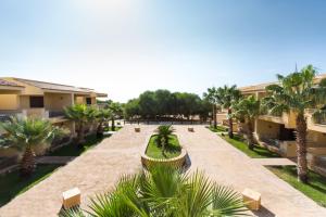 an empty courtyard with palm trees and buildings at Bilo 4 in Triscina
