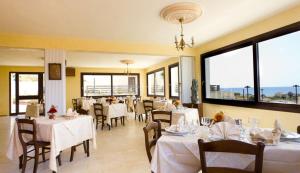 a restaurant with white tables and chairs and windows at Bilo 4 in Triscina
