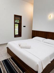 a bedroom with a bed with white sheets and a window at South Elegance in Tellicherry