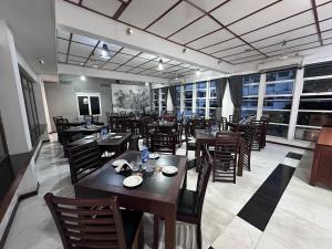 a restaurant with wooden tables and chairs and windows at Subhas Tourist Hotel in Jaffna