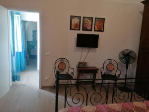 a living room with two chairs and a table and a television at Casa Mosaico in Volterra
