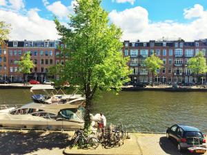 um barco estacionado ao lado de uma árvore ao lado de um rio em Jordaan View em Amsterdã