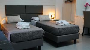 a hotel room with two beds and a ottoman at Mini B&B - Alessandro Volta in Rende