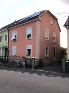 a pink house with a fence next to a street at maison d'artiste chez Bé in Brunstatt