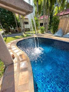 a swimming pool with a water fountain at Baan Sawang hidden in tropical calm in Ban Tai