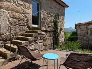 a patio with two chairs and a table and a building at Casa Tritão - Gerês in Campo do Gerês