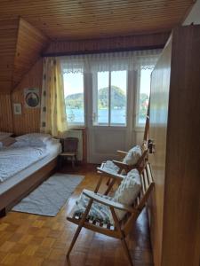 a bedroom with a bed and two chairs and a window at Sovica in Bled