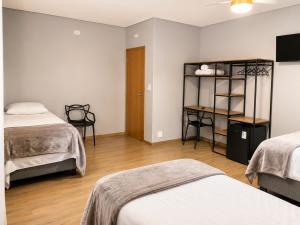 a room with two beds and a desk in it at Hotel Mirante in Careaçu