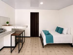 a bedroom with a bed and a table and a kitchen at Anluka House mono araña in Puerto Jiménez