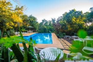 a swimming pool in a yard with tables and chairs at Raices Amambai Lodges in Puerto Iguazú
