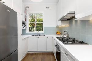 a kitchen with white cabinets and a stove top oven at Stylish Apartment, Malvern East in Melbourne
