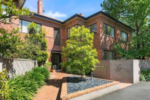 a brick house with a tree in front of it at Stylish Apartment, Malvern East in Melbourne