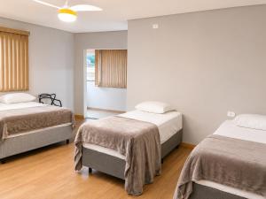 two beds in a room with white walls and wood floors at Hotel Mirante in Careaçu +9 photos