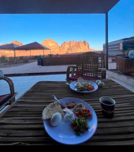 a wooden table with two plates of food on it at Rum Red Sand Luxury Camp & Jeep Tours in Wadi Rum