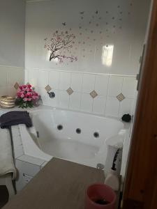 a white bath tub in a bathroom with flowers on the wall at Hospedajes CyC in Llanquihue