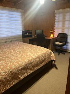 a bedroom with a bed and a desk and two chairs at Hospedajes CyC in Llanquihue